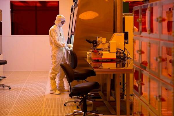 A scientist in a white lab suit uses tools in a Clean Room.